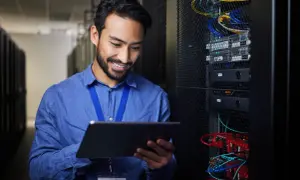 Ein Mann mit Tablet in einem Serverraum, der die **Verantwortung für Datenschutz im Unternehmen** wahrnimmt.