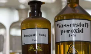 Zwei braune Glasflaschen im Labor. Eine ist mit "Ammoniak-Lösung NH₃ aq." beschriftet. Was ist Ammoniak?