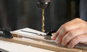Bohrer senkt sich auf Acrylrohr, Späne fliegen. Präzises Bohren erfordert, den Vorschub zu berechnen.