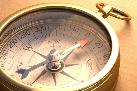 Ein goldener Kompass auf Holz. Wer hat den Kompass erfunden? Diese Frage beschäftigt Seefahrer seit Jahrhunderten.