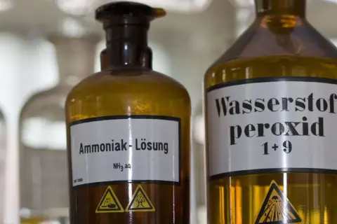 Zwei braune Glasflaschen im Labor. Eine ist mit "Ammoniak-Lösung NH₃ aq." beschriftet. Was ist Ammoniak?