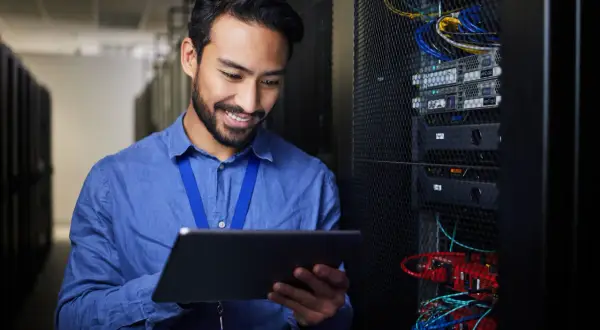 Ein Mann mit Tablet in einem Serverraum, der die **Verantwortung für Datenschutz im Unternehmen** wahrnimmt.