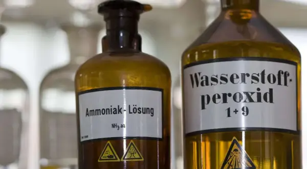 Zwei braune Glasflaschen im Labor. Eine ist mit "Ammoniak-Lösung NH₃ aq." beschriftet. Was ist Ammoniak?