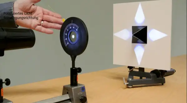 Experiment zur Demonstration des Brewster-Winkels: polarisiertes Licht trifft auf einen schwarzen Würfel, der ein Kreuz aus Lichtpunkten auf einer Leinwand erzeugt.