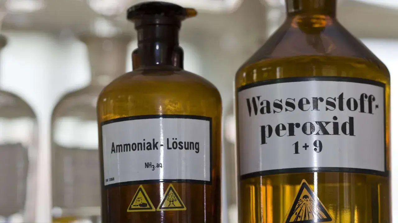 Zwei braune Glasflaschen im Labor. Eine ist mit "Ammoniak-Lösung NH₃ aq." beschriftet. Was ist Ammoniak?