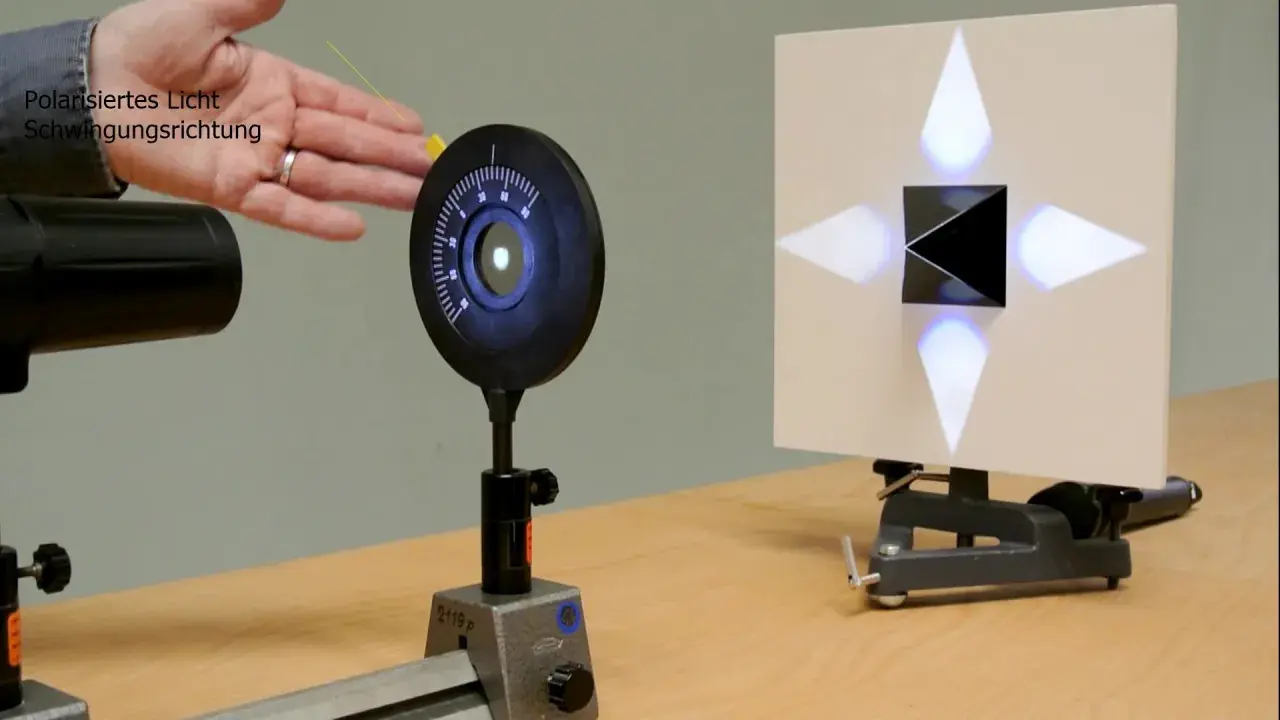 Experiment zur Demonstration des Brewster-Winkels: polarisiertes Licht trifft auf einen schwarzen Würfel, der ein Kreuz aus Lichtpunkten auf einer Leinwand erzeugt.