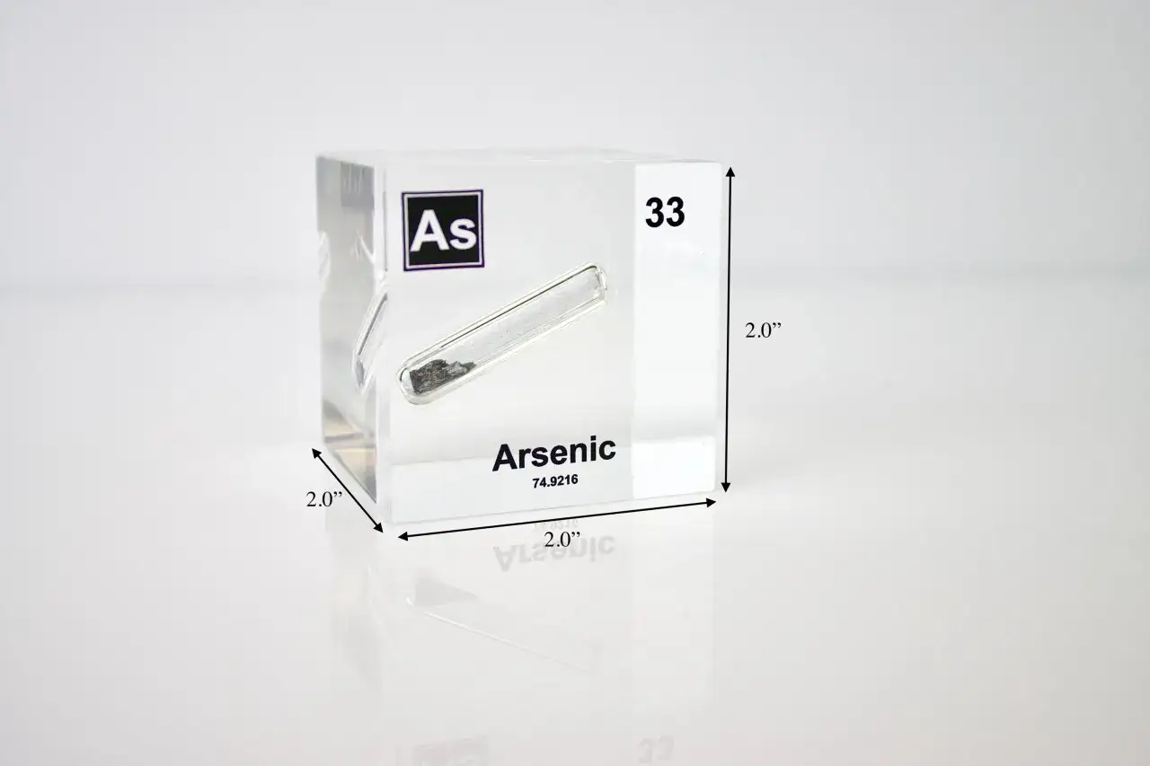 Ein Würfel aus Acryl zeigt das chemische Element Arsen (As) mit der Ordnungszahl 33. Das Element ist in einem Röhrchen eingeschlossen.